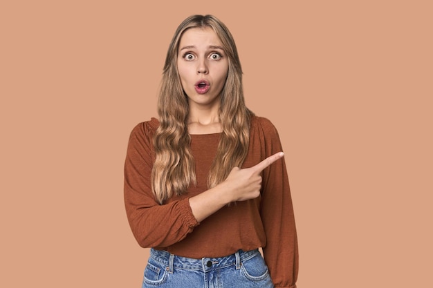 Studio portrait of a blonde Caucasian woman pointing to the side