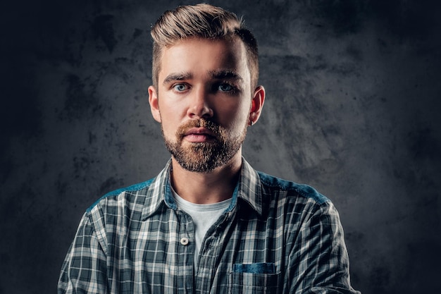 Studio portrait of a blue eyed, bearded hipster male over grey background.