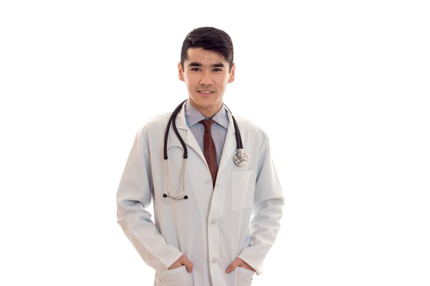 Studio portrait of cheerful male doctor in uniform posing isolated on white wall