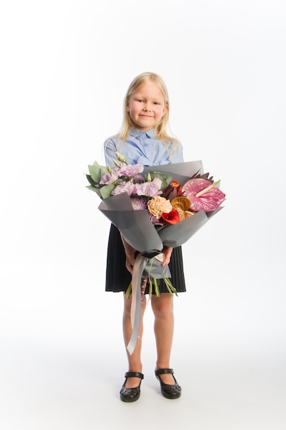 Studio portrait of cute blonde girl in school uniform with beautiful gift bouquet, , selective focus