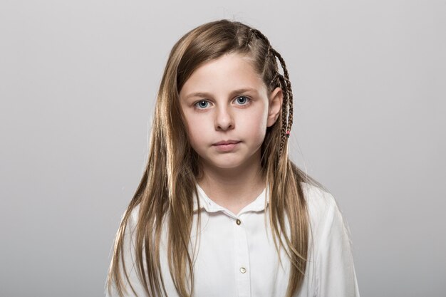 Студийный портрет милой девушки с длинными светлыми волосами в белой рубашке на нейтральном фоне