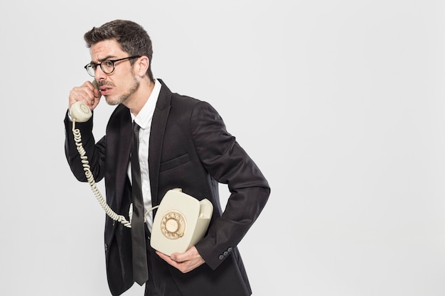 Studio portrait of an expressive man of the 70s talking on a classic phone