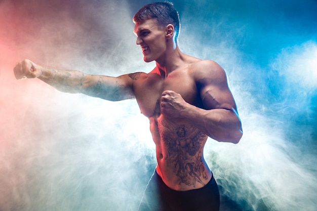 Ritratto dello studio di combattimento dell'uomo muscolare in fumo