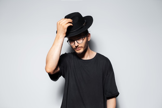 Studio portrait of handsome guy wearing black hat on light grey background