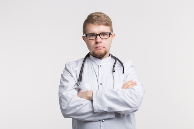 Ritratto in studio di un bel giovane medico bianco con occhiali e camice bianco da medico con stetoscopio