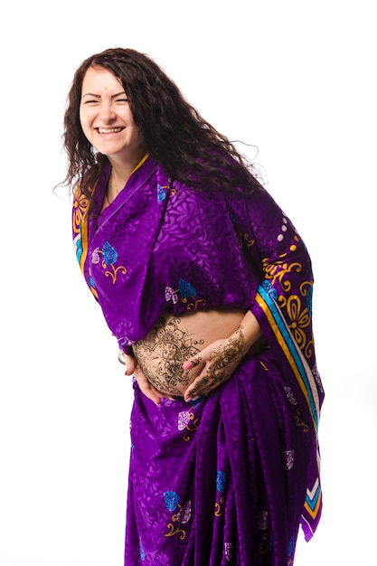 Photo studio portrait of a happy pregnant woman in indian sari, a pregnant belly painted with henna