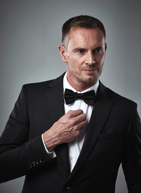 Studio portrait of mature man tuxedo and handsome serious and isolated on grey background Luxury glamour and wealth success with celebrity actor style elegant and date for valentines day