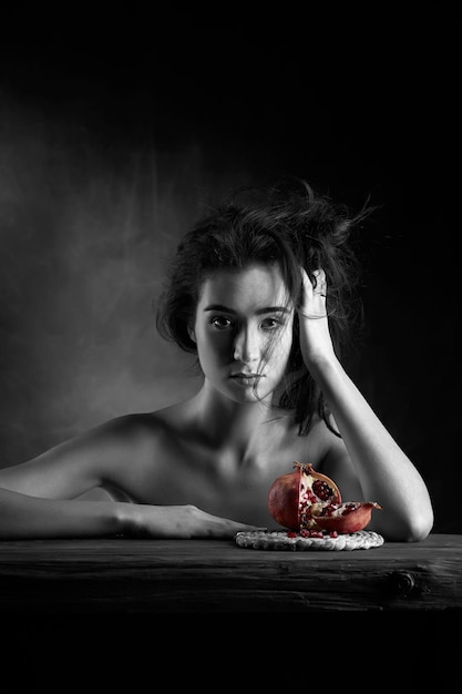 Studio portrait of a nude beautiful girl with a pomegranate