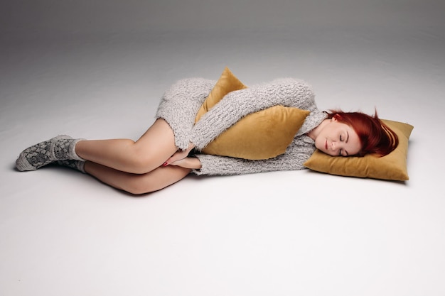 Фото Студийный портрет женщины в свитере, обнимающей подушку