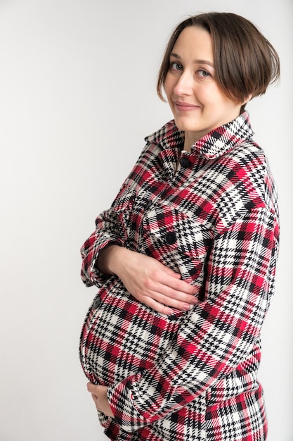 写真 暖かい家庭服、幸せな妊娠の概念、白い壁の若い大人の女性のスタジオポートレート