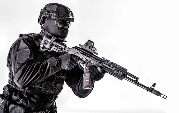 Photo 警察の特殊部隊のメンバーのスタジオポートレート、黒い制服を着たクイックリアクショングループシューター、ヘルメット、マスクとメガネの顔の後ろに隠され、白で隔離されたアサルトライフルで武装、コピースペース
