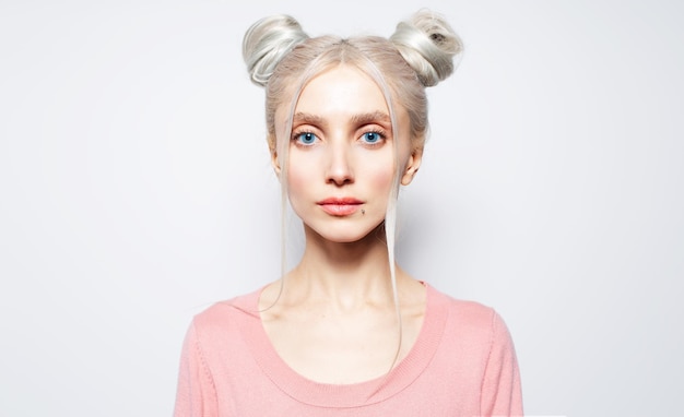 Studio portrait of pretty girl with blonde hair buns on white background