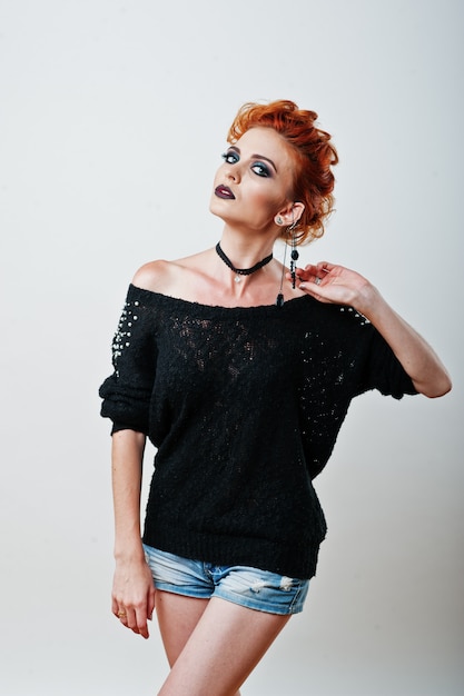 Studio portrait of red haired girl on black blouse and jeans shorts with bright dark make up