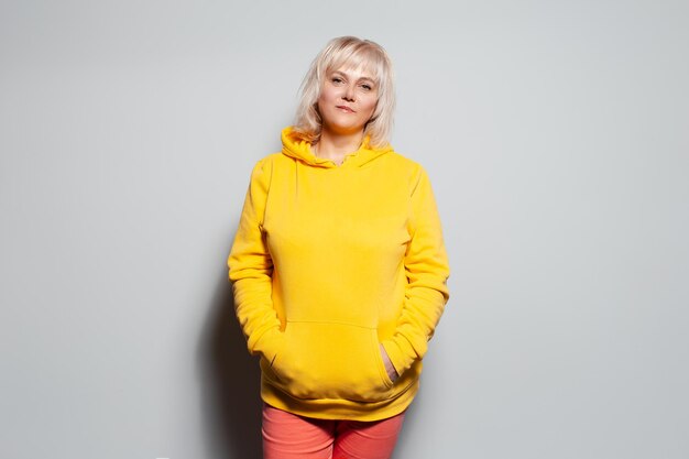 Studio portrait of serious blonde woman in yellow sweater on white background