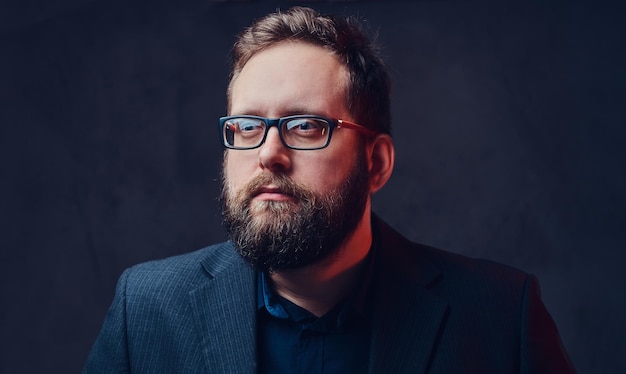 Studio portrait of serious plump male in eyeglasses over grey background.