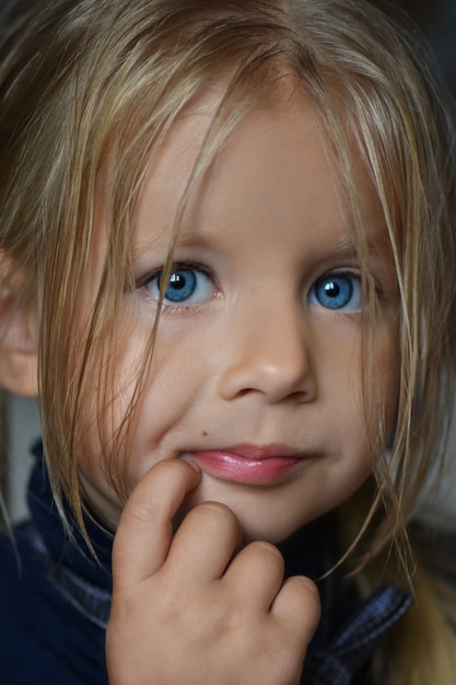 Studio portrait of a small serious white girl with white hair and blue eyes