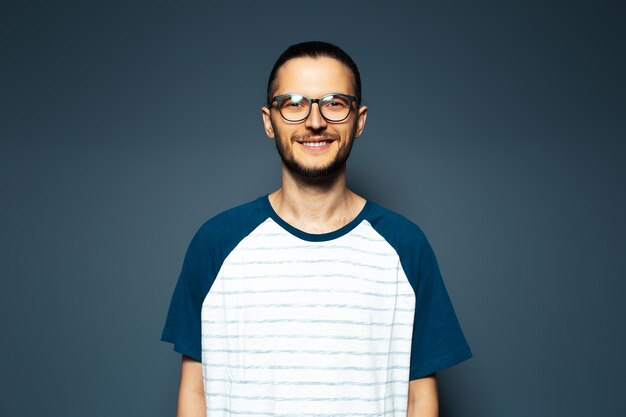 Studio portrait of smiling guy in shirt on blue background wearing eyeglasses