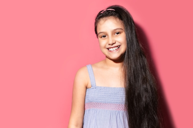 Studio portrait of smiling little child girl on background of pastel pink color with copy space.