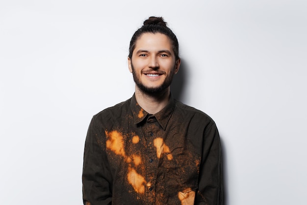 Studio portrait of smiling man with hair bun in shirt on white background