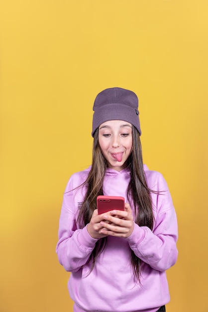 Studio portrait of a teenage girl taking a photo with her cell phone sticking out her tongue
