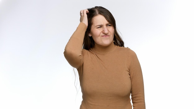 Studio portrait of thoughtful young woman scrubbing her head and thinking Doubts and frustration