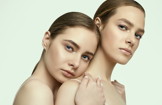 Studio portrait of two beautiful sensual young girls with clear fresh young face skin