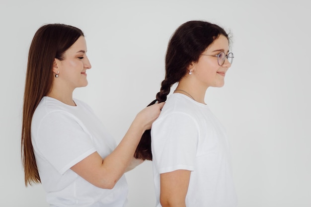 Foto ritratto in studio di due ragazze brune in camicia bianca classica