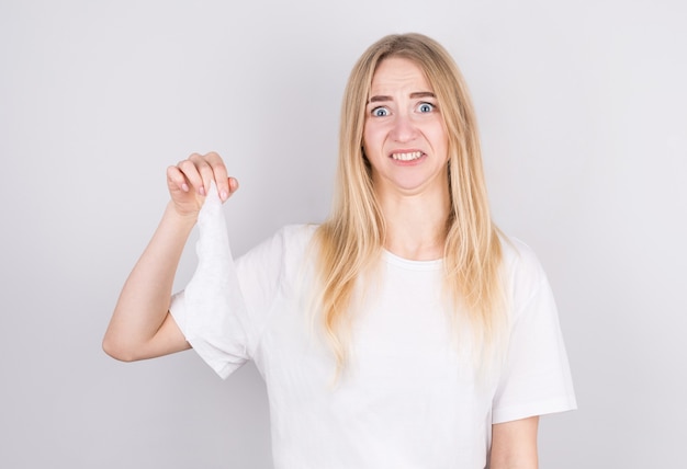 Studio portrait of unhealthy cute blonde female in white shirt with napkin