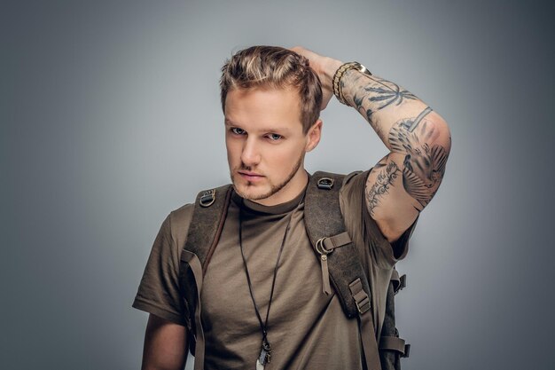 Studio portrait of urban style backpackers with tattoo on arms in grey vignette background.