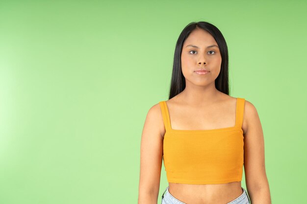 Studio portrait with green background of a happy woman looking at the camera relaxed