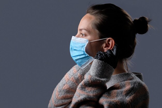 Studio portrait of a woman wearing gloves and a protective mask