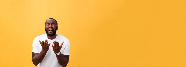 Studio portrait of young african american man in white shirt\
holding hands in prayer looking at the