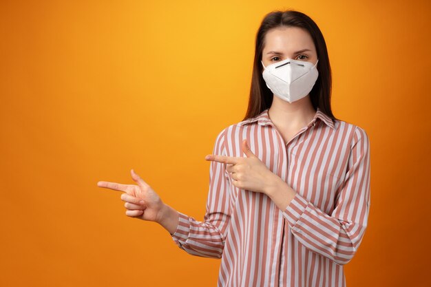 Studio portrait of a young beautiful woman wearing medical face mask against yellow