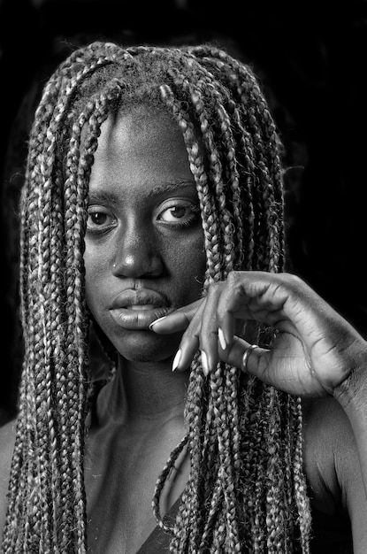 Studio portrait of a young black woman with braids and a black background