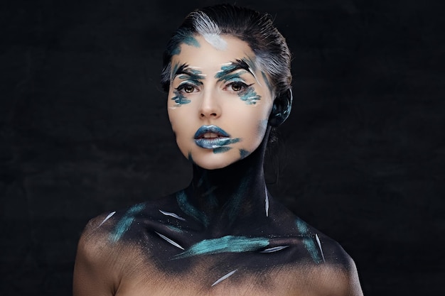 Studio portrait of young female with colorful make up and painted art on a neck.