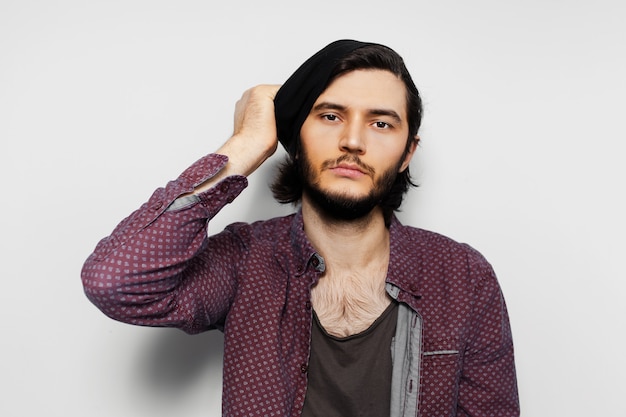 Studio portrait of young guy, taken off the hat on white surface.