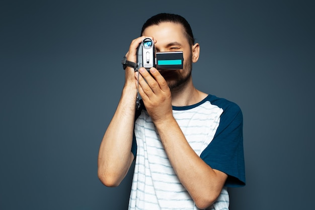 Studio portrait of young guy with digital video camera in hands Making movie