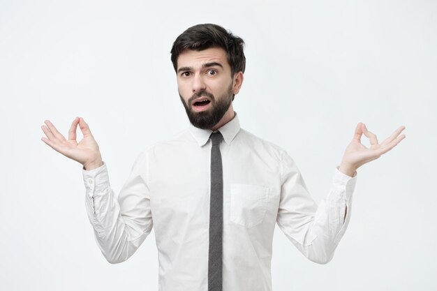 Studio portrait of young handsome male in white shirt in meditation pose trying to relax