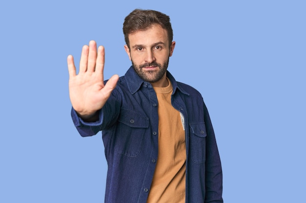 あなたを妨げるストップサインを示す手を伸ばして立っている若いヒスパニック系男性のスタジオ肖像画