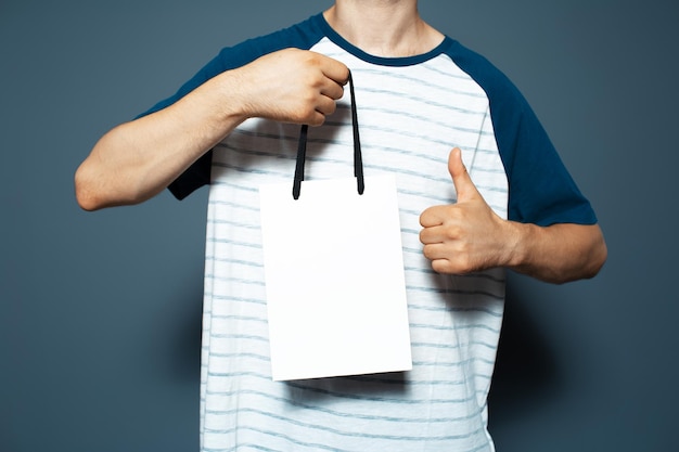 Studio portrait of young man holding a white reusable bag and showing thumb up