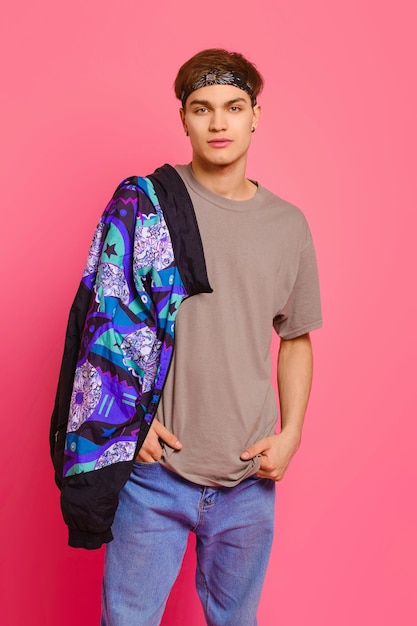 Studio portrait of young man in olive tshirt jeans and bandana on head over pink background