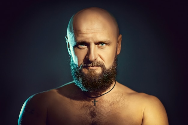 Photo studio portrait of young man with beard on dark