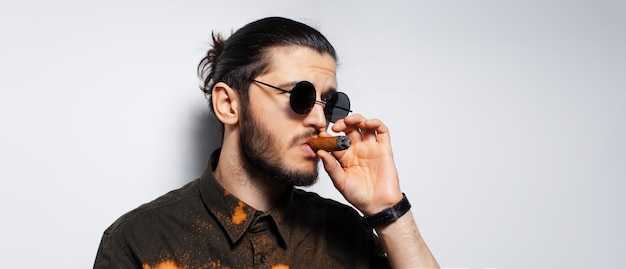 Studio portrait of young man with a cigar on white background Panoramic banner