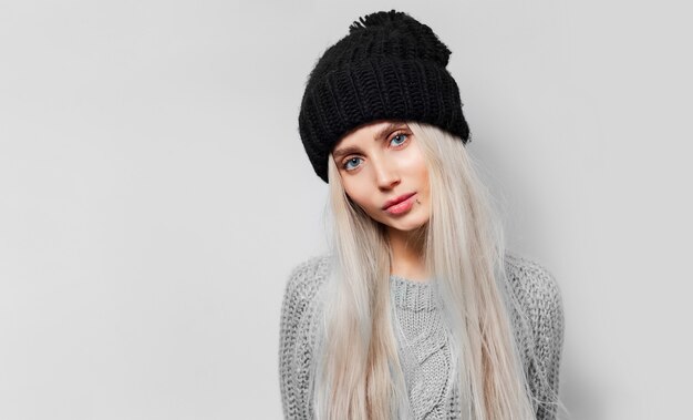 Studio portrait of young pretty blonde girl with black bennie on white background