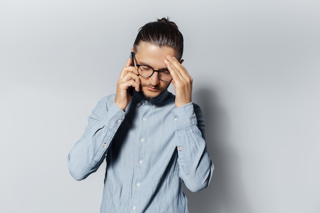 Studio portrait of young sad man talking on smartphone over white background