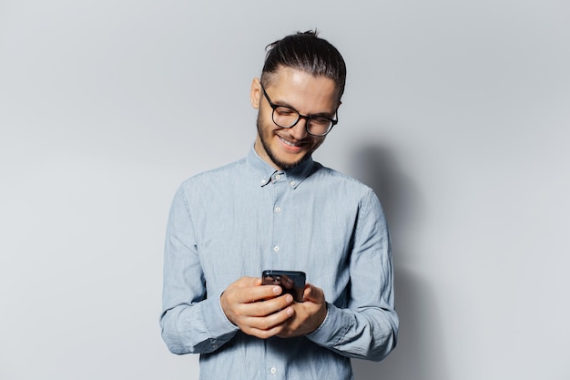 Studio portrait of young smiling man using smartphone on white background