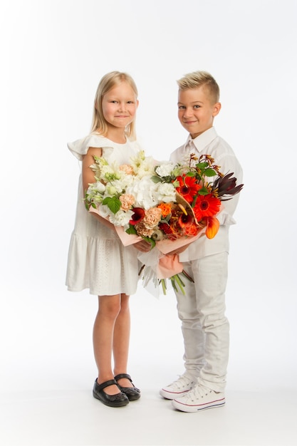 Studio portret jongen geeft meisje feestelijk boeket, felicitatie concept, witte achtergrond, kopie ruimte