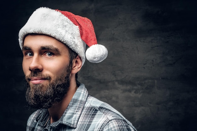 Studio portret van bebaarde man gekleed in een plaid shirt en kerstmuts geïsoleerd op grijze vignet achtergrond.