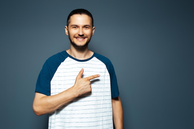 Studio portret van lachende jonge man wijzende vinger weg op blauwe achtergrond