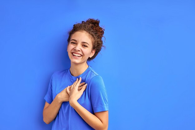 Studio shoot of emotional happy curly girl isolated, lovely female have fun, laugh, has perfect toothy smile